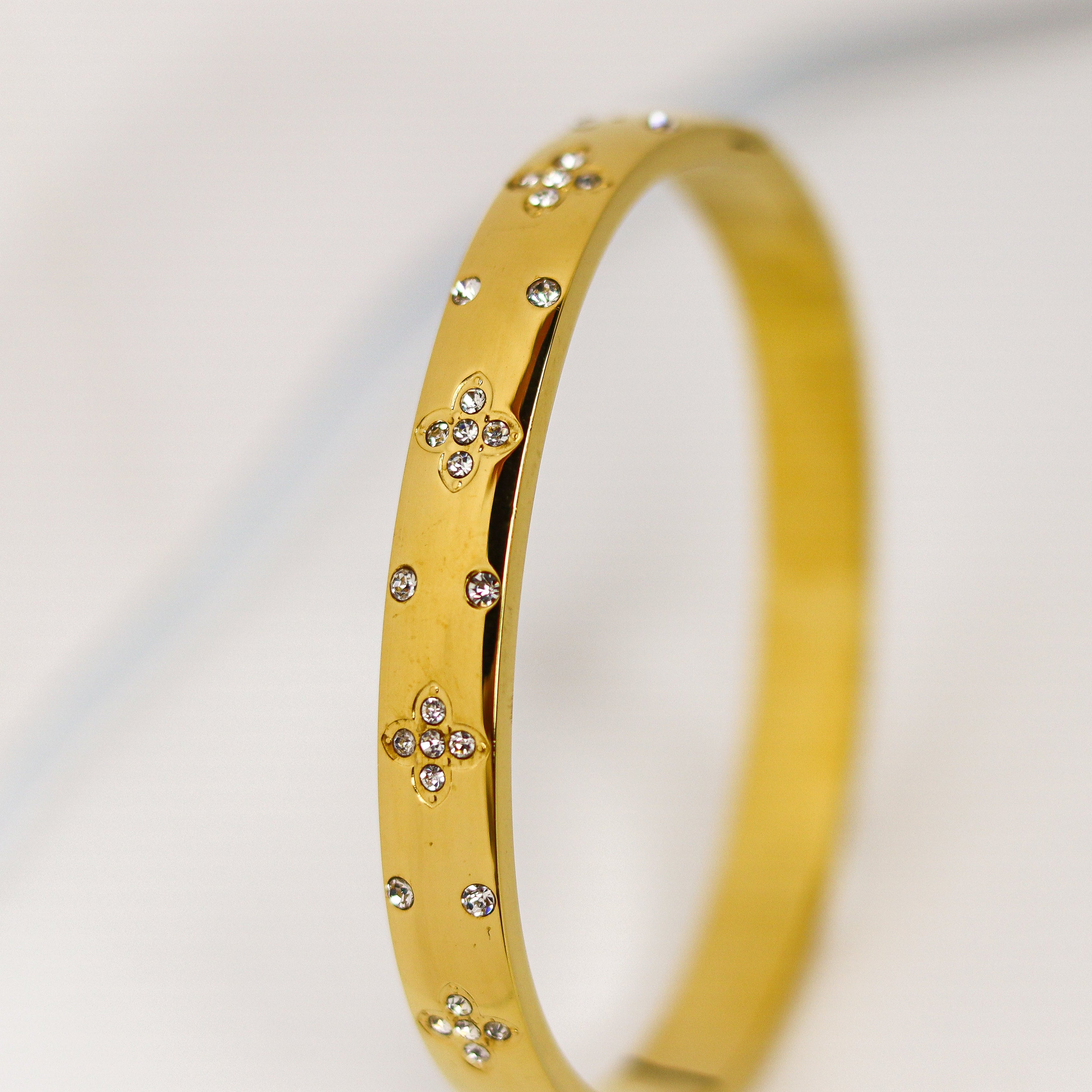 Gold bracelet with small diamonds on a light gray background