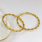 Two gold bracelets on a white dish with a white background