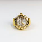 Gold watch ring with a white face on a white background