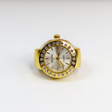 Gold watch ring with a white face on a white background