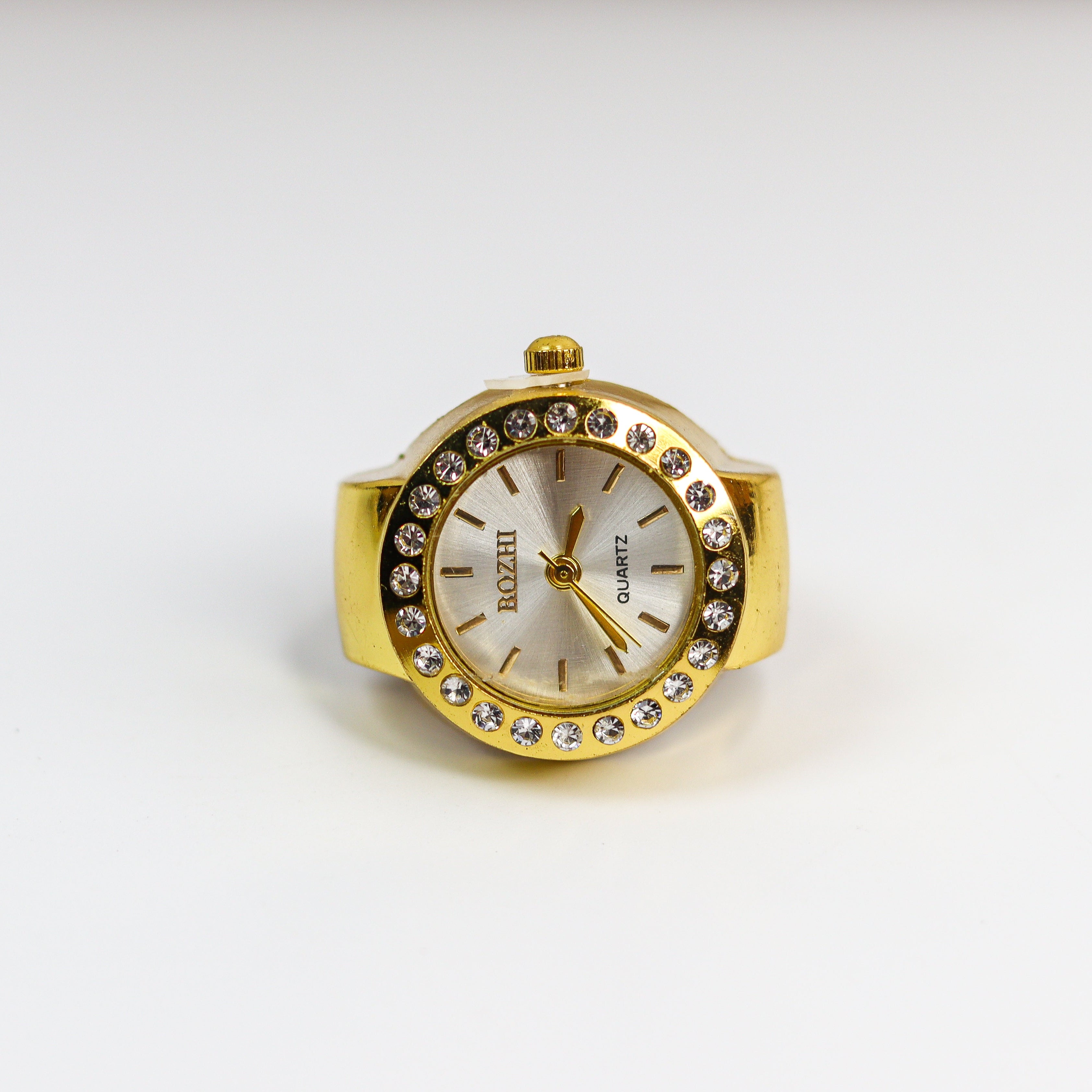 Gold watch ring with a white face on a white background
