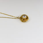 Gold necklace with a circular pendant on a white background
