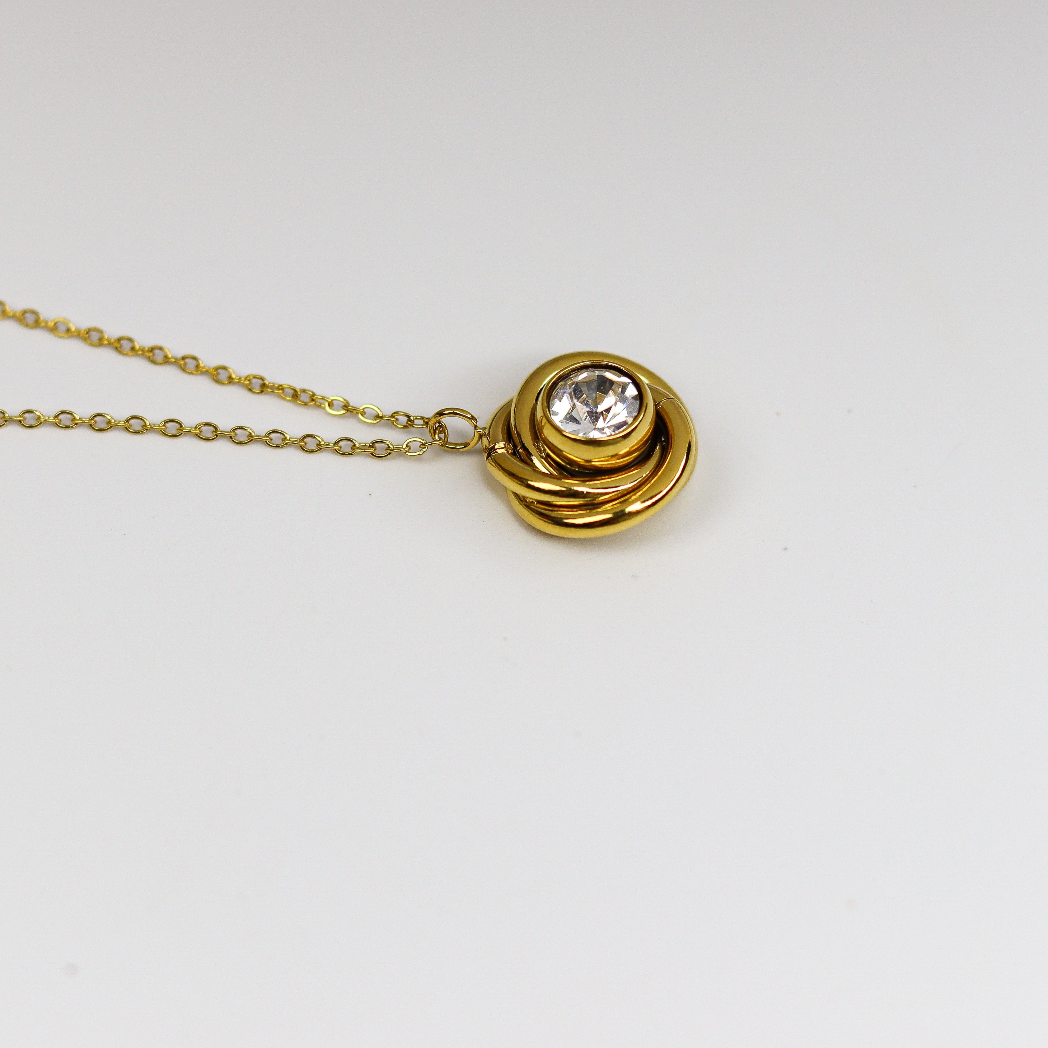 Gold necklace with a circular pendant on a white background