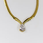 Gold necklace with a teardrop-shaped diamond pendant on a white background