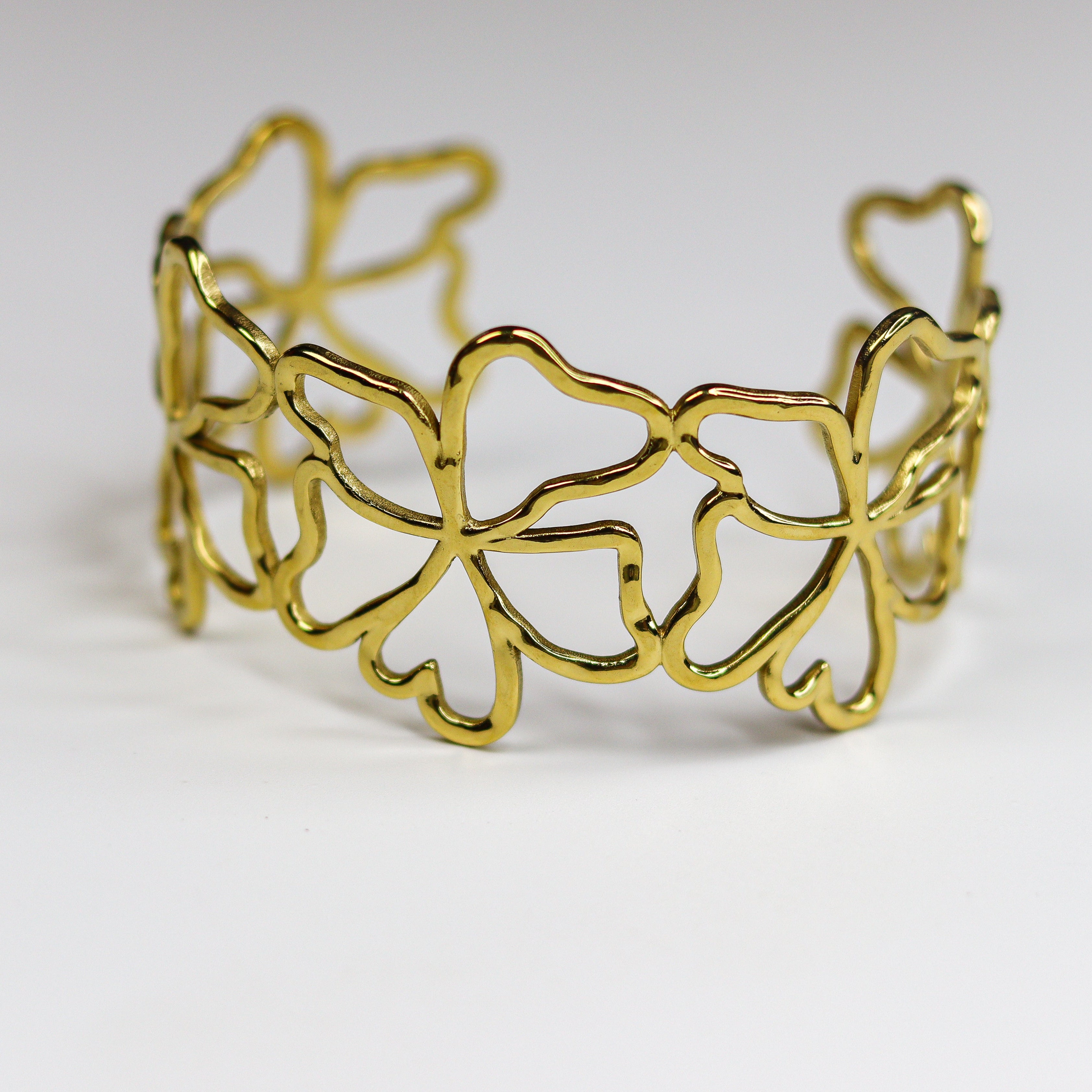 Gold bracelet with a leaf pattern on a white background