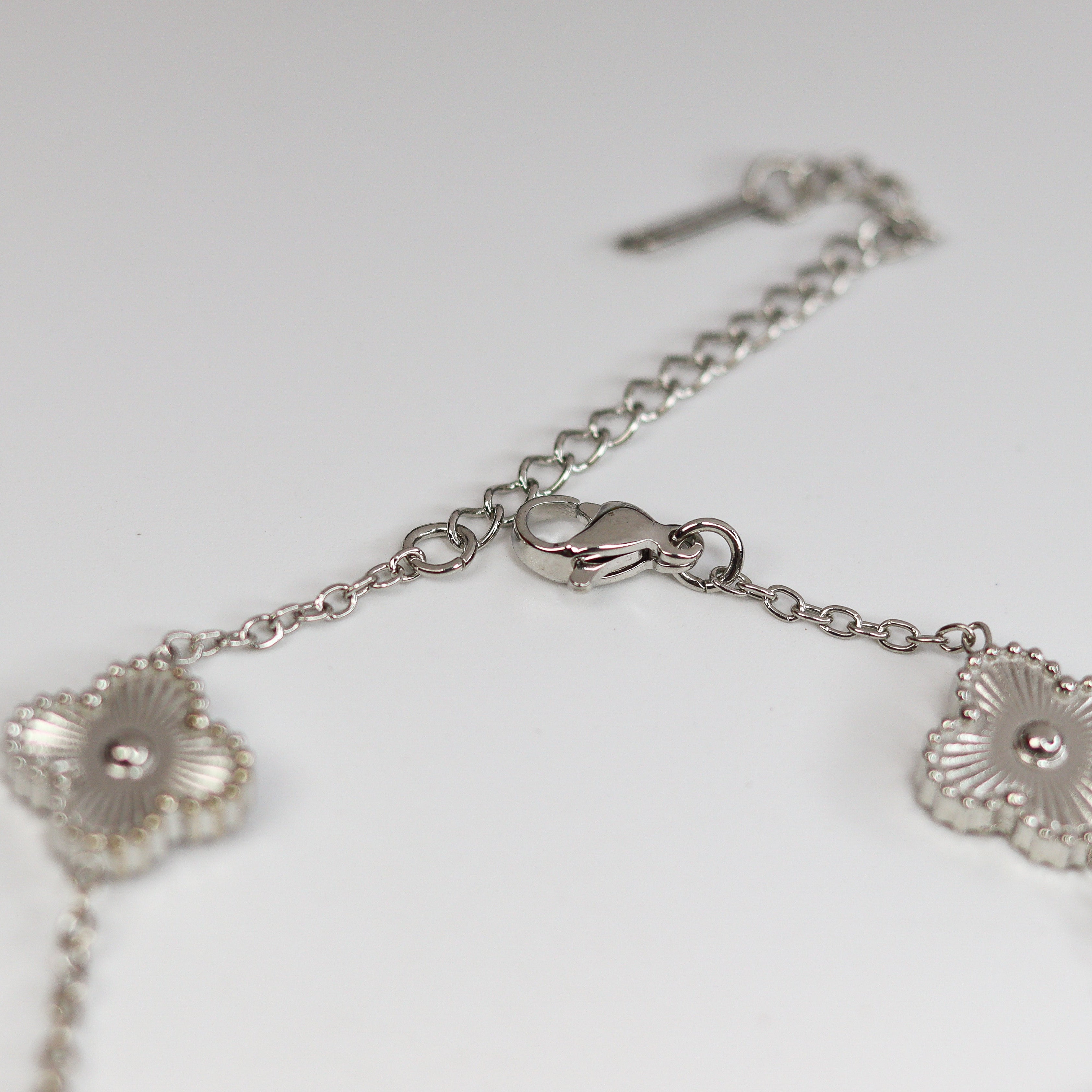 Silver bracelet with floral designs on a light gray background