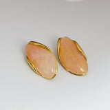 Pair of peach-colored earrings with gold accents on a white background