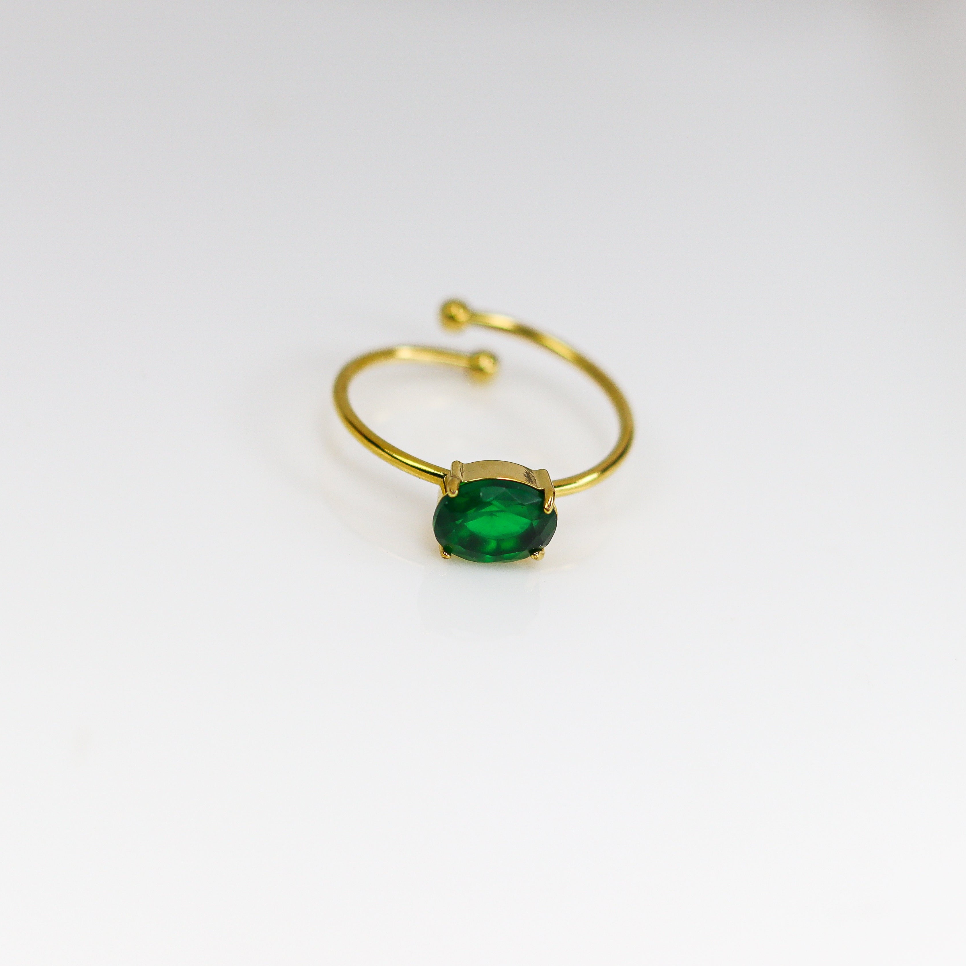Gold ring with a green gemstone on a white background