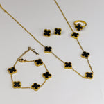Gold necklace with black clover-shaped charms on a white background