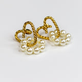 A pair of gold heart-shaped hoop earrings with dangling clusters of white faux pearls, shown on a plain white background.